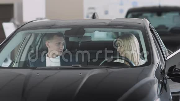 推销员向车内的时髦女商人谈论汽车的特点视频的预览图