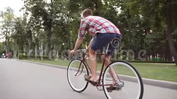 在公园小巷骑老式自行车的年轻人户外自行车运动的家伙健康积极的生活方式后视图视频的预览图