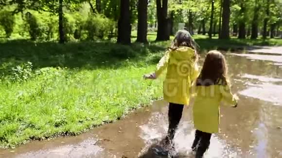 两个女孩在公园的水坑里玩耍和奔跑视频的预览图