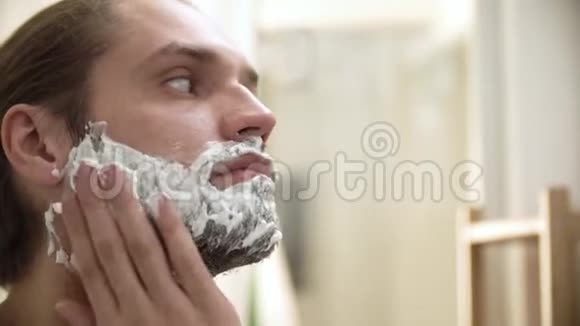男性卫生男性在胡须特写上涂抹剃须泡沫视频的预览图