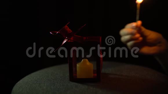 一支黄色的蜡烛在黑色背景的金属红色灯笼中燃烧特写视频的预览图