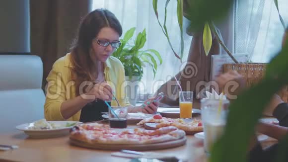 女孩在咖啡馆吃披萨快餐慢动作视频保持智能手机社交媒体人们一起吃披萨视频的预览图