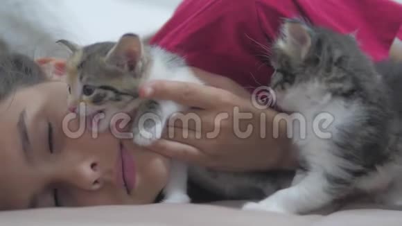 小女孩和黑白绒毛两只小猫躺在床上女孩猫抚摸小猫慢动作视频视频的预览图