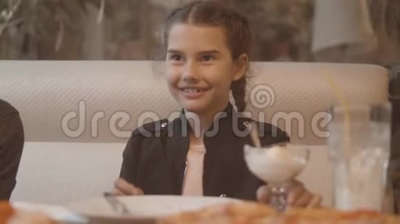 小女孩在快餐店吃冰淇淋慢动作视频孩子在咖啡馆吃冰淇淋有趣的卷发孩子视频的预览图