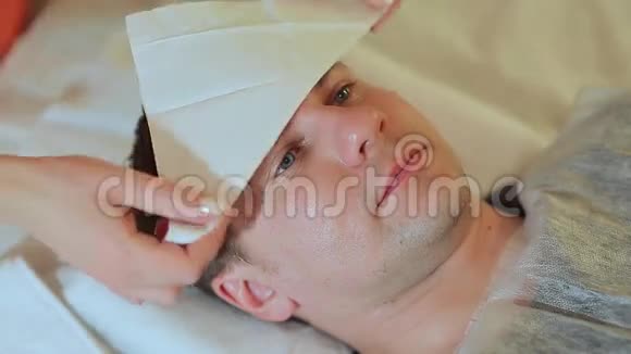 在水疗中心按摩的人干燥面部擦拭按摩脸部和颈部视频的预览图