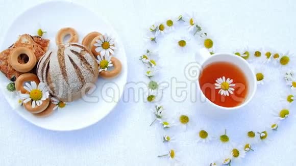 有糕点饼干和曲奇的白色盘子用白色雏菊装饰在白色的碟子上有一个白色的杯子视频的预览图
