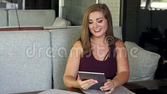 体重超标的女孩坐在有平板电脑的咖啡馆里视频的预览图