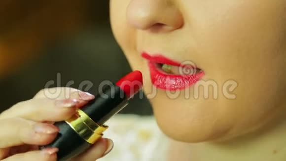 镜子前的女人用红口红涂上嘴唇视频的预览图