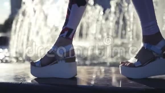 漂亮的腿在时尚凉鞋的边缘喷泉与眩光和模糊的水高清1920x1080慢慢慢慢视频的预览图