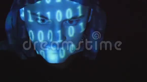 戴着头巾的黑客在电脑上工作二进制代码投射在他的脸上对愤怒的敌对者的源代码视频的预览图