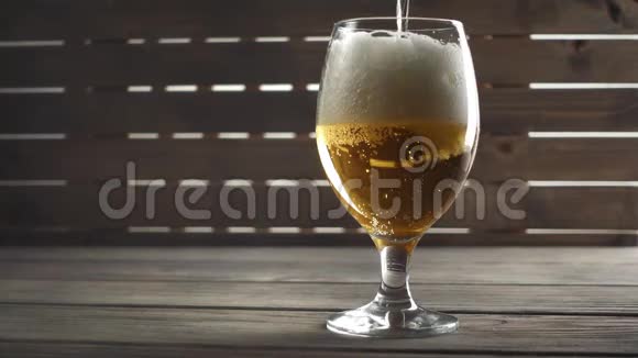啤酒倒在木头背景上的玻璃上慢动作视频的预览图