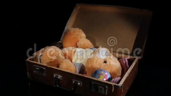 穿着旧皮箱的泰迪熊在黑色背景上旋转视频的预览图