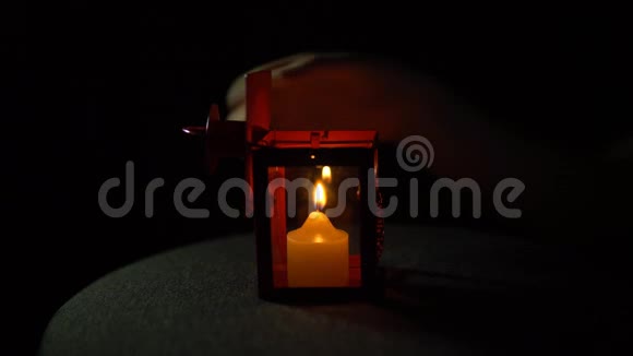 一支黄色的蜡烛在黑色背景的金属红色灯笼中燃烧特写视频的预览图