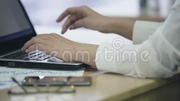 女性手在笔记本电脑上打字工作繁忙的办公室员工视频的预览图