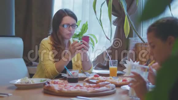 女孩在咖啡馆吃披萨快餐慢动作视频保持智能手机社交媒体人们一起吃披萨视频的预览图