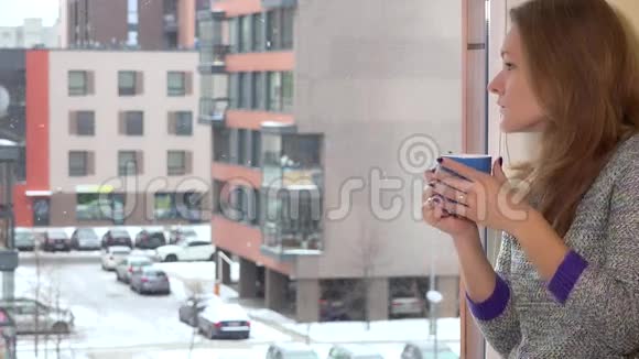 严肃的女人透过平屋的窗户喝着茶咖啡和做梦视频的预览图