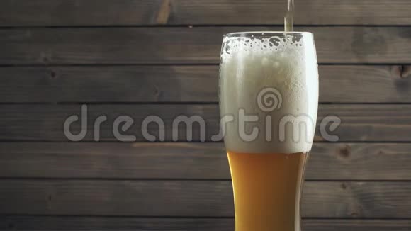 啤酒倒在木头背景上的玻璃上慢动作视频的预览图
