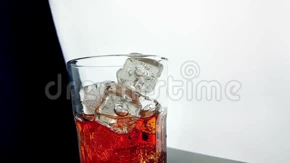 将橙色饮料酒精鸡尾酒倒入杯中杯中有黑色背景的冰块视频的预览图