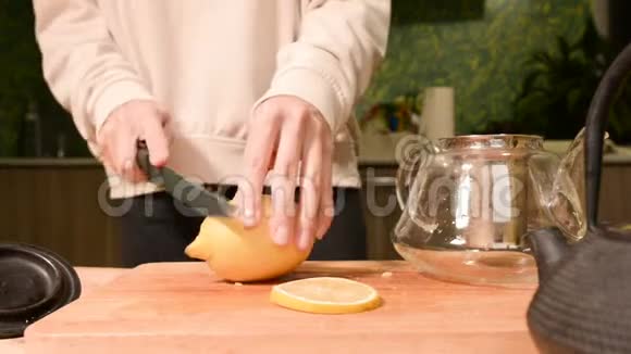 女性手的特写是用柠檬把一把刀切成碎片挤在木桌上泡茶视频的预览图