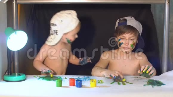 两兄弟在纸上画手指他们的手沾满了油漆视频的预览图