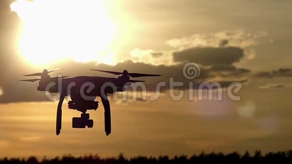 在美丽的夕阳下一架带旋转叶片的飞行无人机视频的预览图