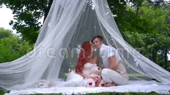 在公园举行的婚礼照片会上浪漫的情侣在装饰品上接吻视频的预览图