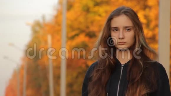 一个穿着兜帽的女孩头发松松的看着远处的路上秋天的背景秋天的森林视频的预览图