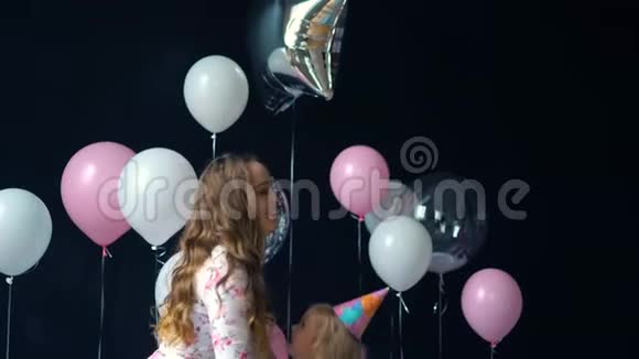 一对年轻的母亲和女儿玩得开心用五颜六色的氦气球摆姿势的肖像视频的预览图