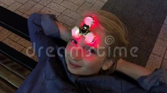 活泼开朗的女生玩着一个发光的坐立不安的旋转器在额头上旋转晚上在户外流行的时髦玩具视频的预览图