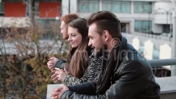 朋友们聊天两个年轻人和一个漂亮的女人谈笑风生地站在桥栏杆附近慢节奏视频的预览图