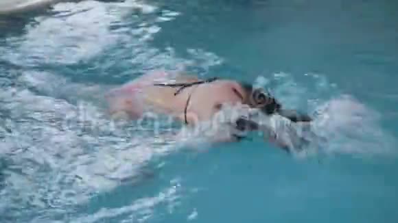 美丽的女人在游泳池里游泳视频的预览图