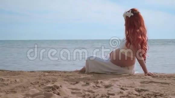 海边的孕妇侧景坐在地平线上的美丽女人视频的预览图