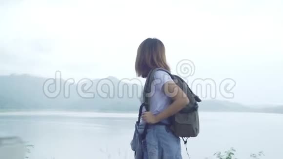 徒步旅行的徒步旅行女背包客在雨天在湖边的森林里自由行走视频的预览图