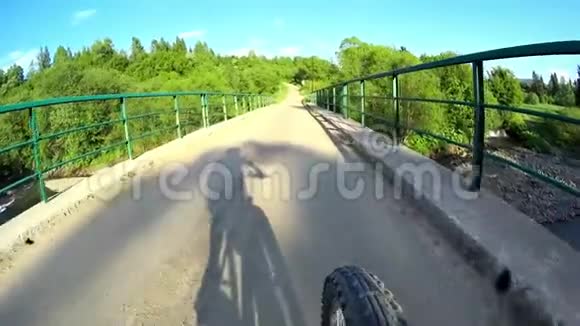 阳光明媚的一天骑自行车的人骑着自行车沿着土路穿过比斯扎迪山上的桥视频的预览图