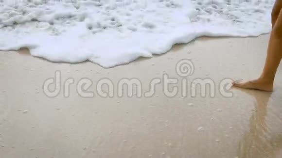 女人的特写镜头美丽的晒黑的腿在沙滩上漫步踏入大海波的图像视频的预览图