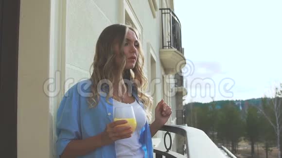 浪漫的女孩在阳台上早上喝果汁视频的预览图