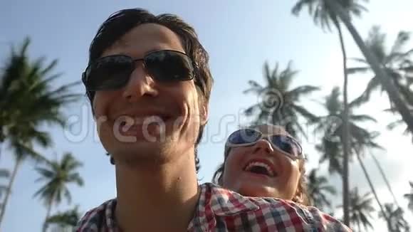 年轻快乐时尚的夫妇戴着太阳镜驾驶滑板车在暑假阳光下兴奋慢动作视频的预览图