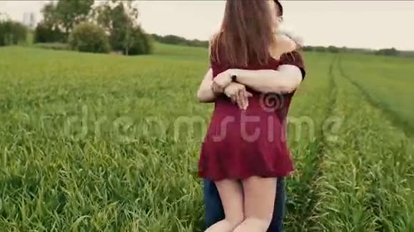 一对浪漫的夫妇在绿色的田野里旋转亲吻欢笑和快乐慢莫稳定射击视频的预览图