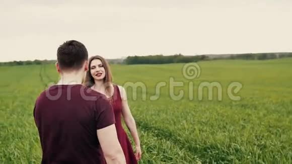浪漫的年轻夫妇他们在绿色的田野里拥抱和旋转慢莫稳定射击视频的预览图