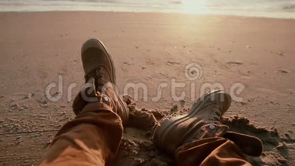 一种由两只穿着的靴子组成的特写属于一个在沙滩上看美丽日落的人视频的预览图