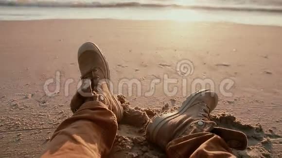 海滩上有两只靴子的近景这是一幅美丽的海岸落日的景色视频的预览图