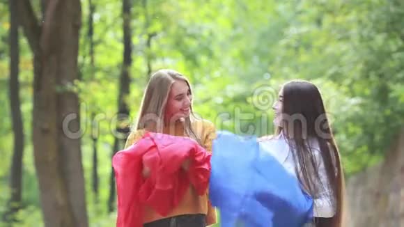 在夏天公园里用蓝色和红色的布跳跳年轻女人视频的预览图