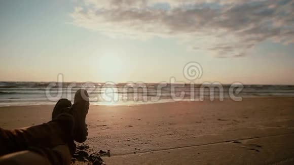 一个人双腿交叉的近景躺在沙滩上穿着靴子欣赏风景视频的预览图