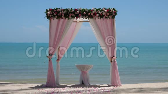 海边沙滩上的粉色结婚拱门视频的预览图