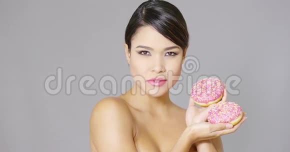 美丽的微笑着拿着甜甜圈的女人视频的预览图