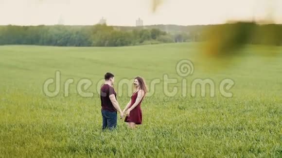 可爱的情侣拥抱站在田野里他们开心地笑着互相看着牵手慢节奏视频的预览图