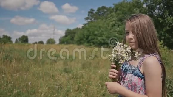 小女孩走在草地上手里拿着一束鲜花甘菊视频的预览图