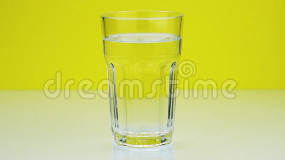 一片止痛的泡腾片落入玻璃杯中在黄色的阿司匹林上溶解特写慢镜头视频的预览图