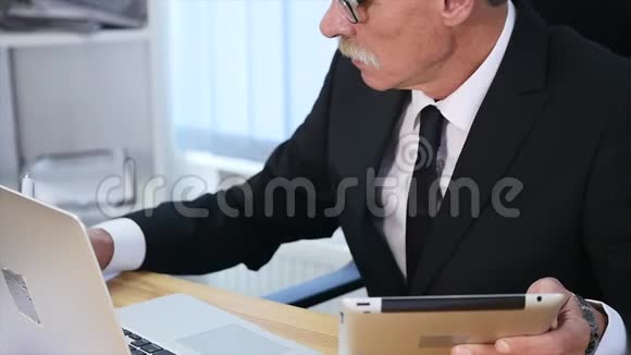 商人用手在木制桌子上的笔记本电脑上打字并做一些笔记慢动作视频的预览图
