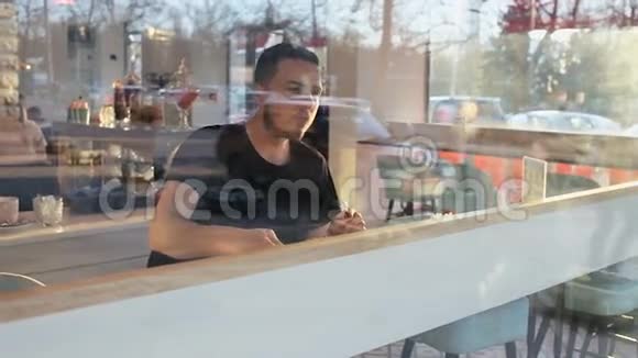 一个手拿着咖啡坐在咖啡馆里的男人慢镜头视频的预览图